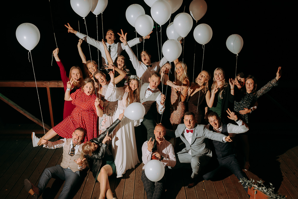 Szalone zdjęcie grupowe, podczas wesela, przedstawiające uśmiechnietych gości. 