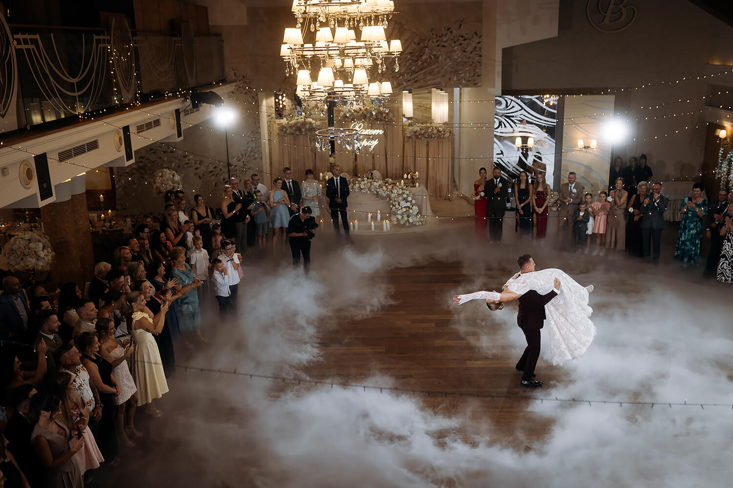 Pierwszy taniec w Hotelu Badura Wadowice. Para młoda tańczy na tle gości weselnych i dekoracji.