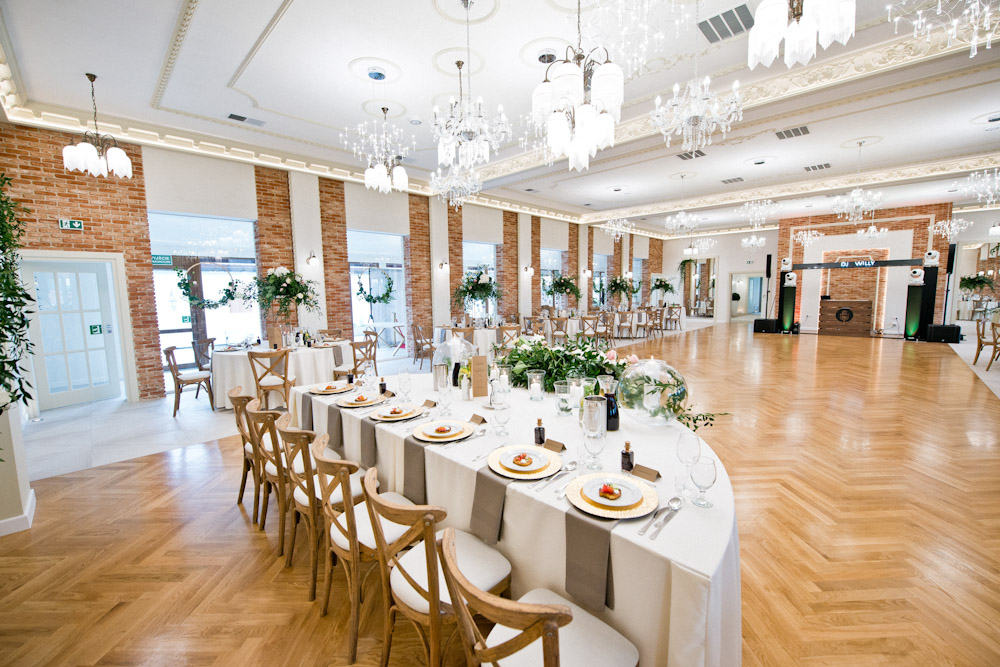 Elegancka sala weselna Villa Serenada Osiek z dekoracjami. Stoły dla gości, parkiet, ceglane ściany.