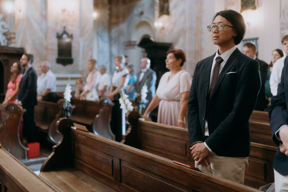 Goście weselni podczas ceremonii ślubnej w kościele, w ławkach.