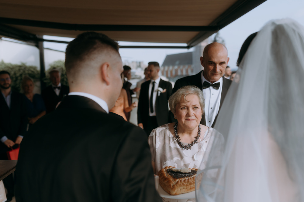 Goście weselni witają parę młodą chlebem i solą podczas ceremonii ślubnej.