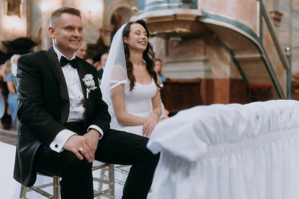 Uśmiechnięta para młoda siedzi w kościele podczas ceremonii ślubnej.