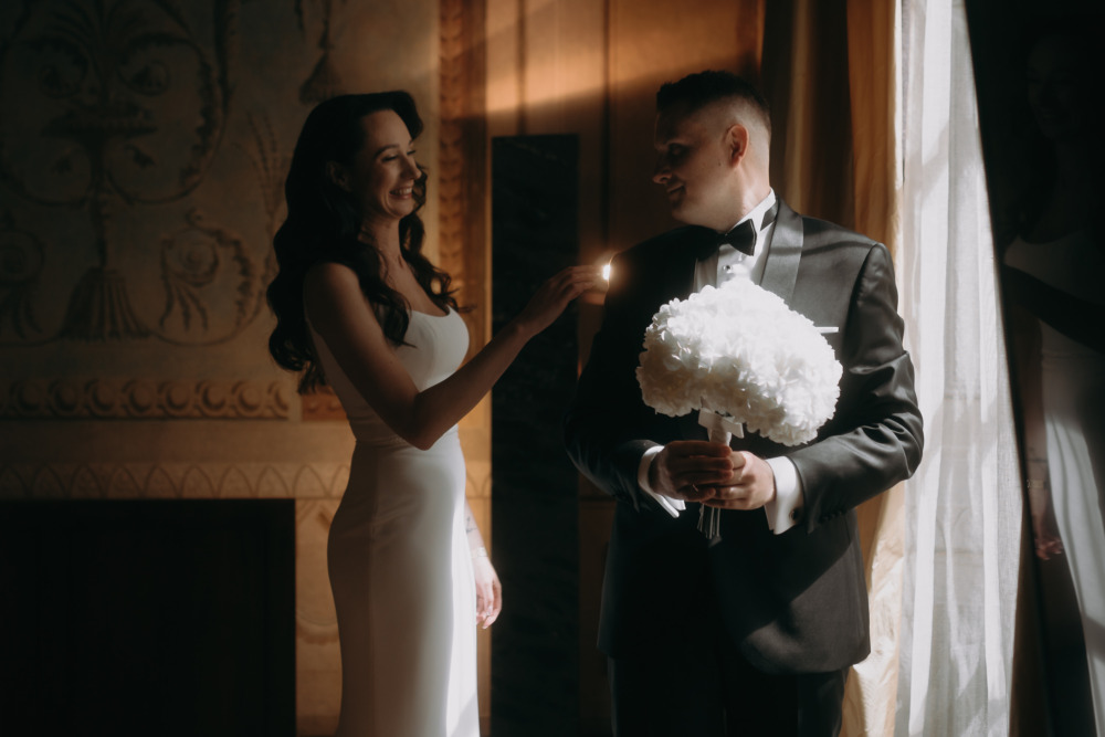 Uśmiechnięta para młoda w eleganckich strojach. Bukiet ślubny w rękach pana młodego.