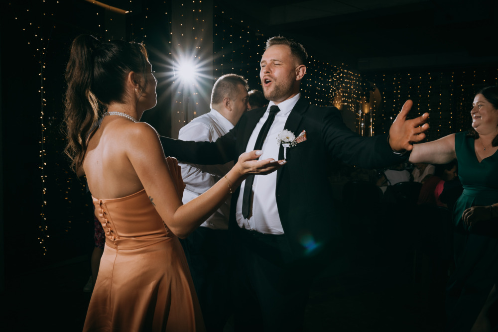 Wesołe tańce pary młodej i gości weselnych podczas przyjęcia.